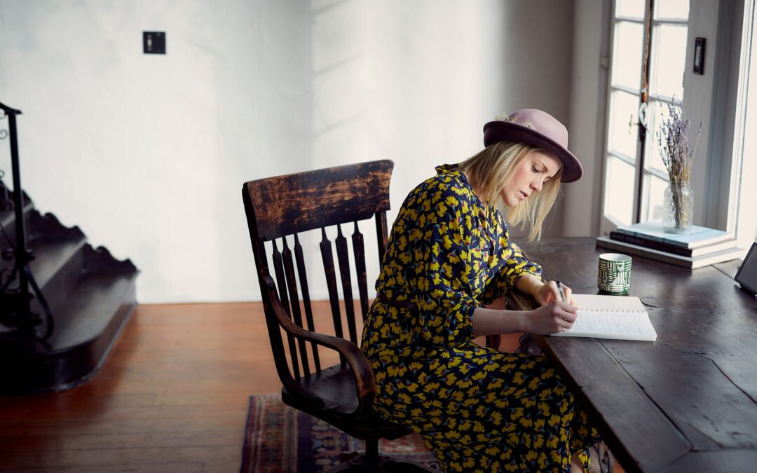 Mujer escribiendo a mano en un papel sobre una mesa