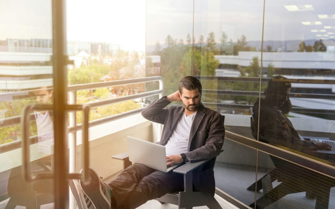 /hombre-sentado-en-el-sillon-gris-usando-la-computadora-portatil-plateada-en-el-balcon-del-edificio-durante-el-dia